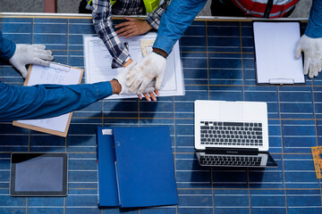 A group of people are shaking hands and one of them is holding a laptop. Scene is professional and collaborative