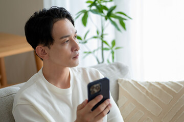 ソファでスマホを見ている男性