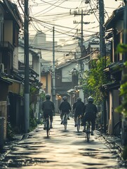 Four cyclists riding through a narrow street lined with traditional houses and utility poles.