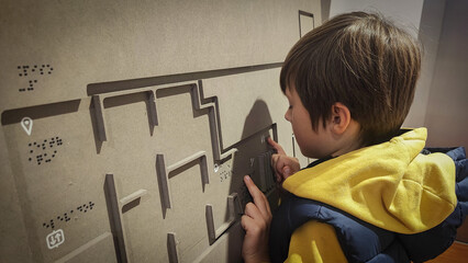A boy reading the evacuation plan on the wall in braille. Close-up of a child reading braille. The...
