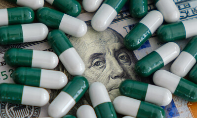 Pills and capsules laying on US dollar banknotes