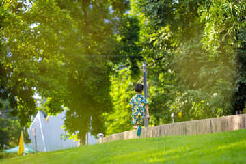 Asian boy enjoy run on green meadow grass city tree park