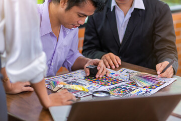 Team graphic designer checking print quality of media graphics proof print and color guides in...