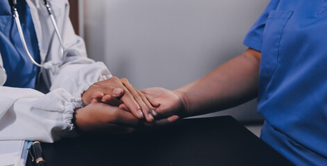 Kind male doctor wearing white coat consulting elder senior female patient holding hand of older...