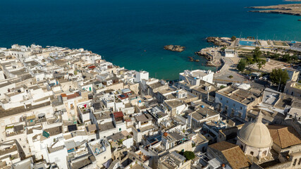 Obraz premium Aerial view of houses, apartments and buildings in the historic center of Monopoli, in the province of Bari, Apulia, Italy. In background is the Mediterranean Sea.