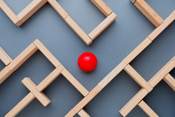 A red wooden ball is looking for a way out in a maze.