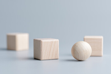 A round wooden ball in a group of wooden cubes, comparison of fixed and moveable things, easy...