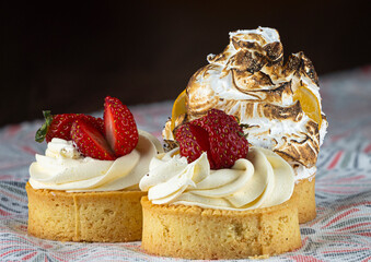 Two strawberry cream tarts sit elegantly on a vibrant tablecloth