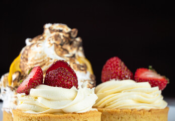Two strawberry cream tarts sit elegantly on a vibrant tablecloth