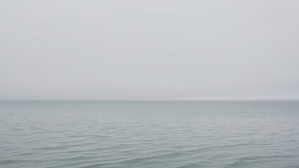 Obraz premium Calm overcast day at the tranquil sea with gentle ripples stretching to the horizon.