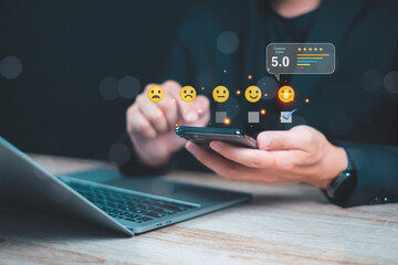 Person using a smartphone to provide feedback and ratings with emoji icons while working on a...
