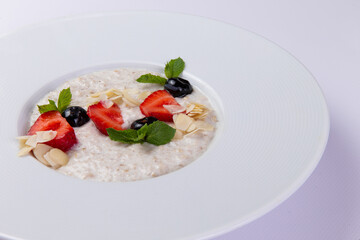 Milk porridge with berries in a plate on a white background.