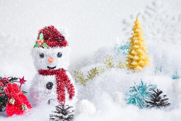 Nice cute smiling artificial snowman with red hat and scarf and different decorations in snowy winter atmosphere. Closeup. Front view.