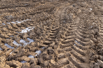 plowed soil covered with snow and frost in a field with tractor tracks