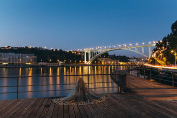 Fishing net laying on pier with illuminated Arrabida bridge at blue hour in afurada, Gaia, Porto, Portugal