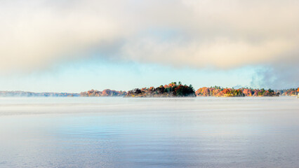 Grouping of sunlit islands and coastline in autumn colors in the morning fog.