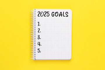 Notebook with 2025 Goals on bright yellow background, spiral bound, checklist, plan.