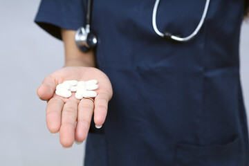 Fototapeta premium Female doctor offering pills capsules white to the patient in hand isolated on a white background. Focus on tablets