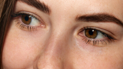 Fototapeta premium Close-up photo of young woman with bright brown eyes, long lashes and smooth facial skin against white background. Concept of beauty, healthcare, freshness and wellness, confidence. Ad