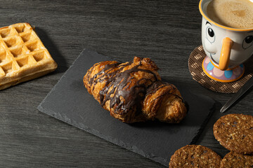 Un croissant fresco y dorado, cubierto con una capa de chocolate, que resalta su textura crujiente...
