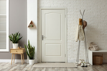 Metal rack with jacket, cap and sneakers in hallway