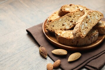 Traditional Italian almond biscuits (Cantucci) and nuts on wooden table, closeup. Space for text