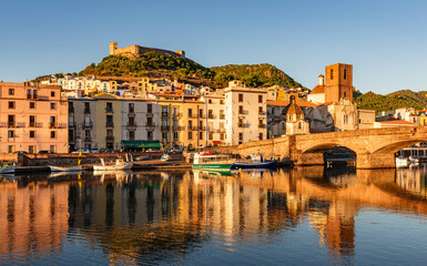 View of the picturesque town of Bosa with its colorful houses reflected in the Temo River at golden...