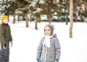Happy boy and girl playing with snowball outdoor in nature. Children winter activity.