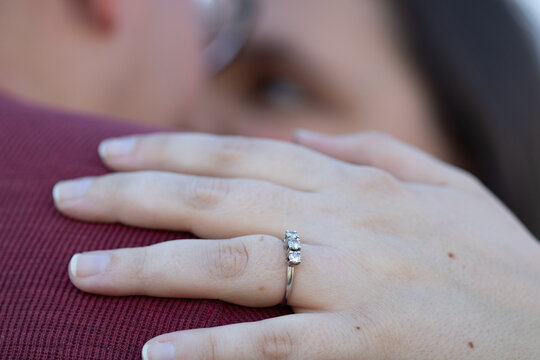 Woman embracing fiance showing off engagement ring