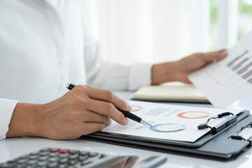 Businesswoman working in office analyzing charts and graphs.