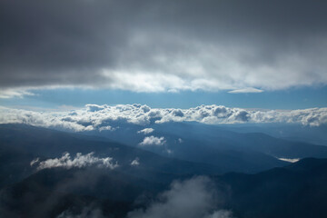 Fog and clouds in the mountains, clouds and nebula on mountain peaks. Beautiful nature.  Between sky and earth. Horizontal image.