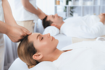 Fototapeta premium Caucasian couple enjoying relaxing anti-stress head massage and pampering facial beauty skin recreation leisure in dayspa modern light ambient at luxury resort or hotel spa salon. Quiescent