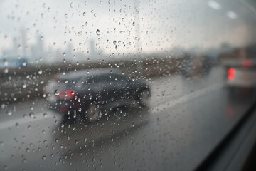 Raindrops clinging to the side window of the car, the car is out of focus, visibility is poor while traveling.