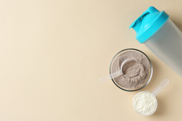 Protein powder in bowl, scoops and shaker on beige background, flat lay. Space for text