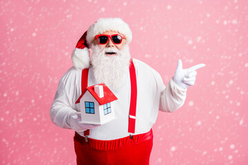 Portrait of his he nice attractive cheerful Santa holding in hands house comfort life demonstrating...