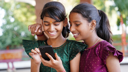 Front view of a happy Indian girl writing message or chat in smartphone or mobile