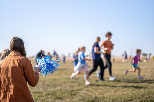 Selective focus on a pom-pom streamer with defocused child running in the background 