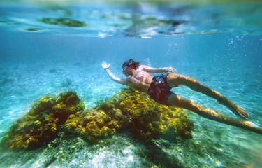 Diving teenage boy snorkeling over the coral reefs underwater photo in the clean turquoise lagoon...