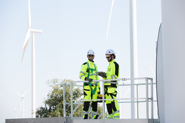 Group of male engineer working with plan inspecting or maintenance of wind turbines at windmill...