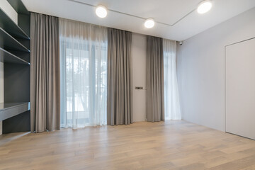 Obraz premium An empty room with a final finish. Unfurnished. Beautiful curtains on the panoramic window. Built-in shelving.