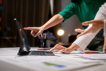 Two women are working on a laptop together