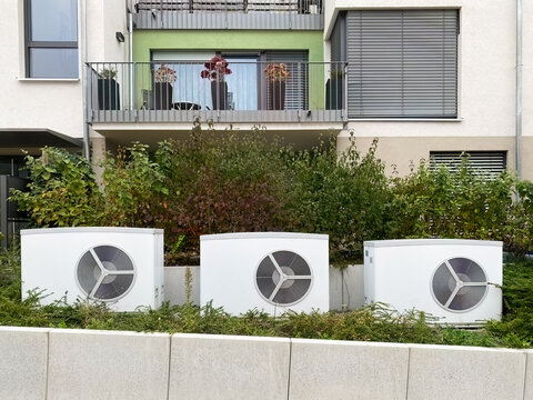 Drei W&auml;rmpumpen vor einem Mehrfamilienhaus