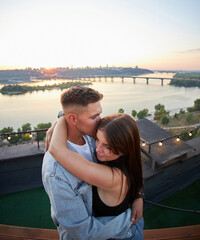 A young couple kisses and embraces during a romantic rooftop date