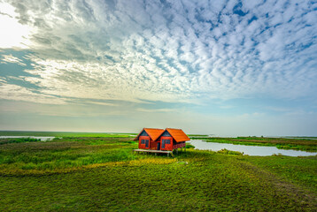 Red house in the middle of green fields 