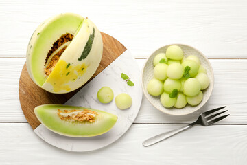 Melon balls in bowl and fresh fruit on white wooden table, flat lay
