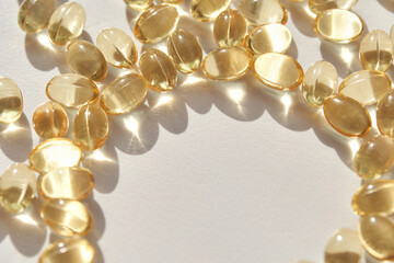 Shiny transparent capsules arranged in circle on white surface with sunlight reflection