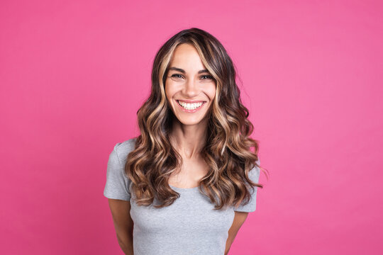 Portrait of a beautiful smiling woman with luxurious hair, positive emotions, human face on a pink background.