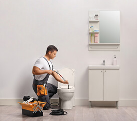 Plumber using a drain snake for clogged toilet