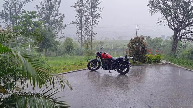 A wide view of a superbike parked outside a house in heavy rain at a hill station in Karnataka