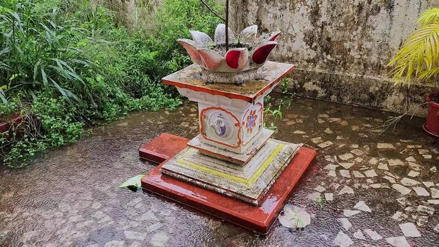 A video of a holy basil pot or tulsi temple in front of an Indian house on a rainy day